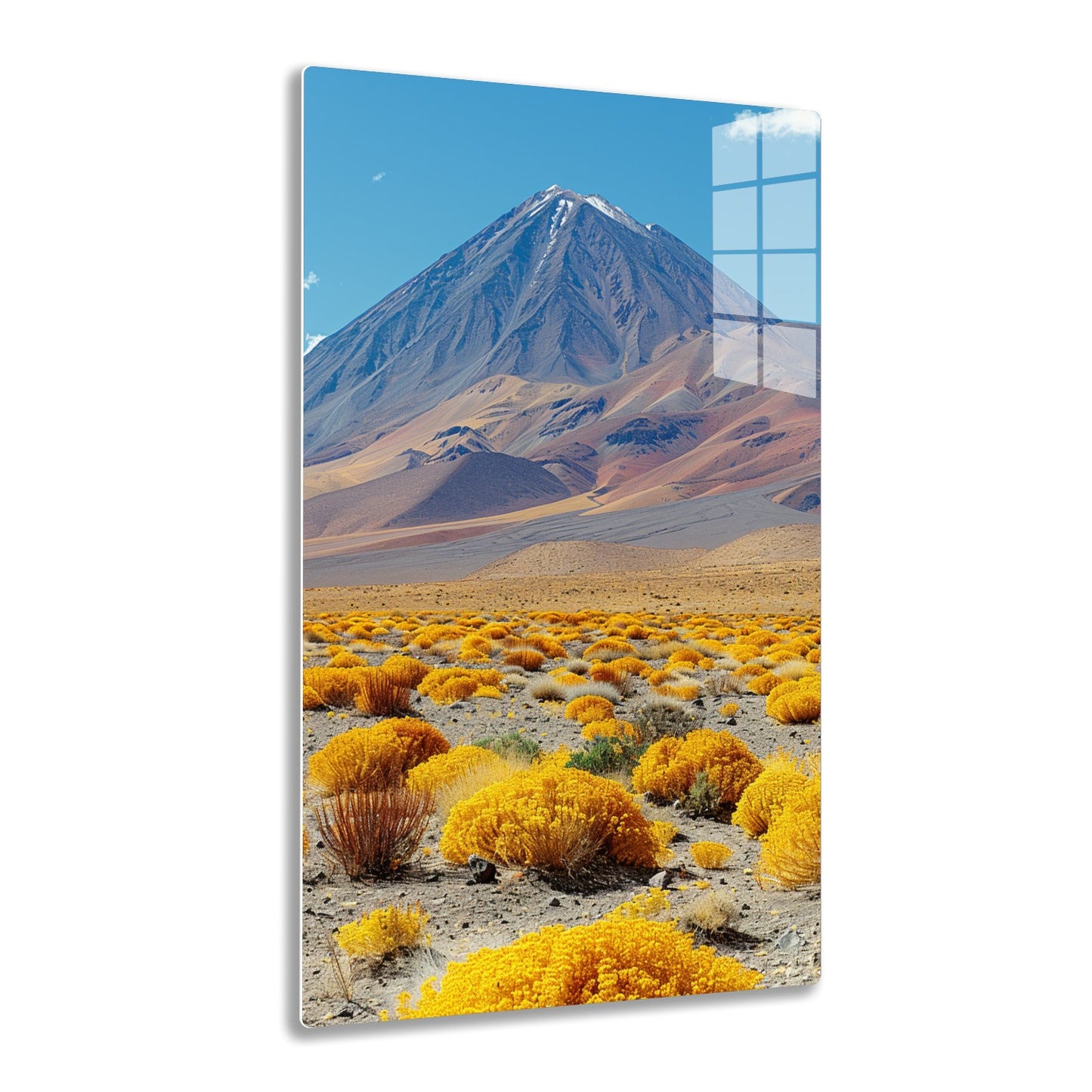 A majestic snow-capped mountain rises against a vivid blue sky, surrounded by a vast landscape of undulating hills and shrubs with vibrant yellow and rusty hues in the foreground.
