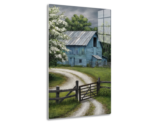 An old weathered barn with blue-gray wood siding and a tin roof stands surrounded by blooming trees and a wooden fence along a dirt path, under a dramatic cloudy sky.
