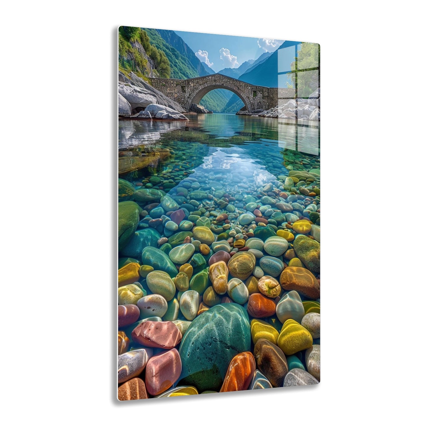 A stone bridge arches over a crystal clear river in a scenic mountain valley, the riverbed covered in colorful smooth pebbles reflecting in the vibrant blue-green waters.
