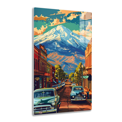 A vibrant street scene depicts a quaint town with vintage cars parked along the road, framed by snow-capped mountains towering in the background against a colorful sky.
