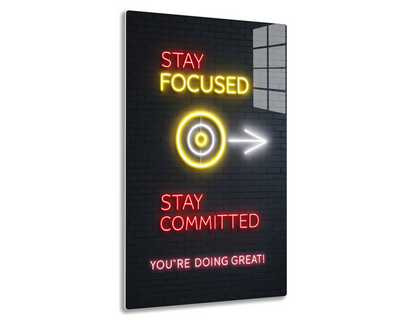 Neon sign on brick wall saying "Stay Focused" with target icon, arrow pointing right, "Stay Committed", and "You're Doing Great!" in motivational message
