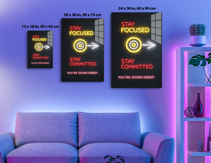 Neon sign on brick wall saying "Stay Focused" with target icon, arrow pointing right, "Stay Committed", and "You're Doing Great!" in motivational message
