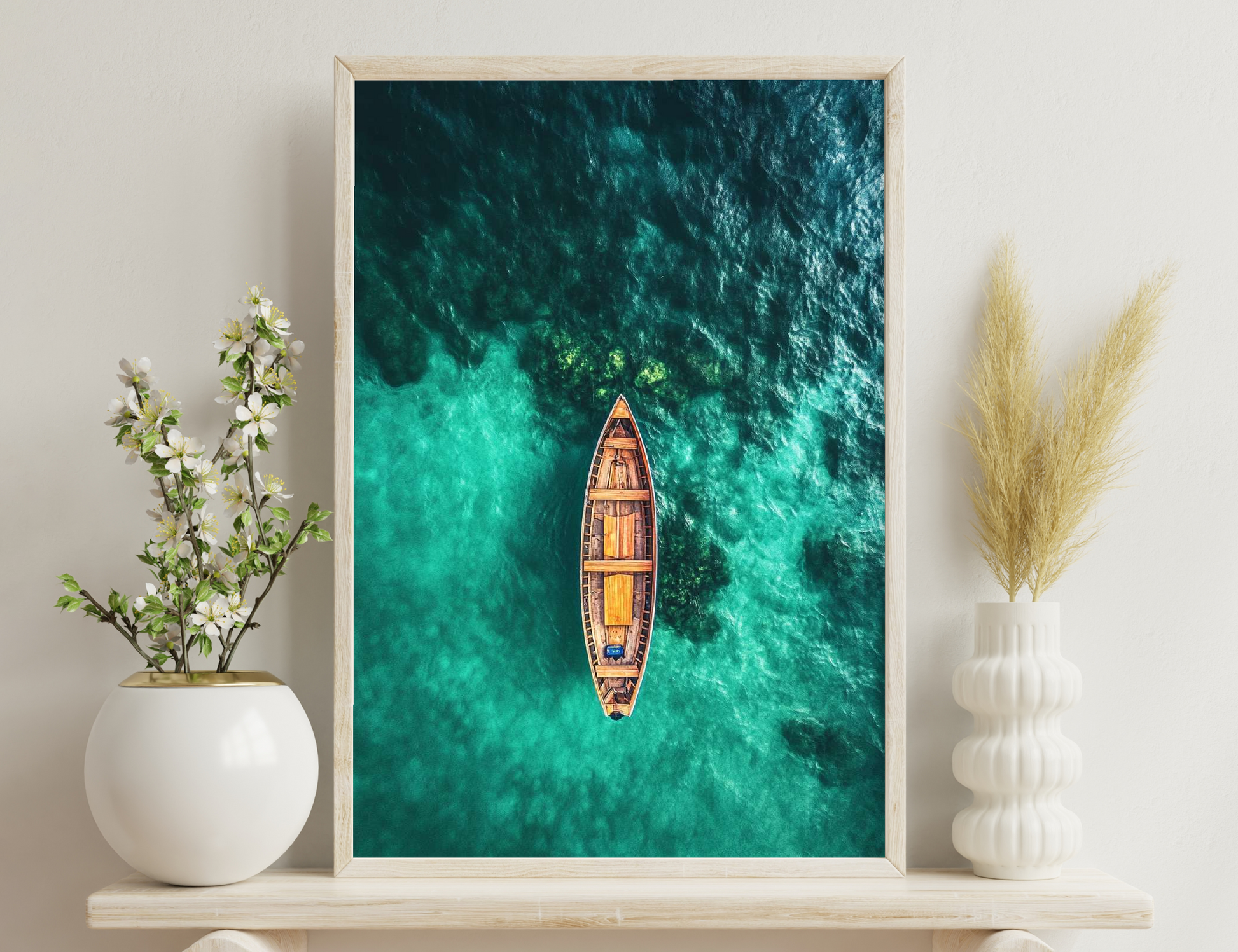 A traditional wooden boat floating on stunningly clear turquoise waters, surrounded by lush greenery, captured in an aerial view.
