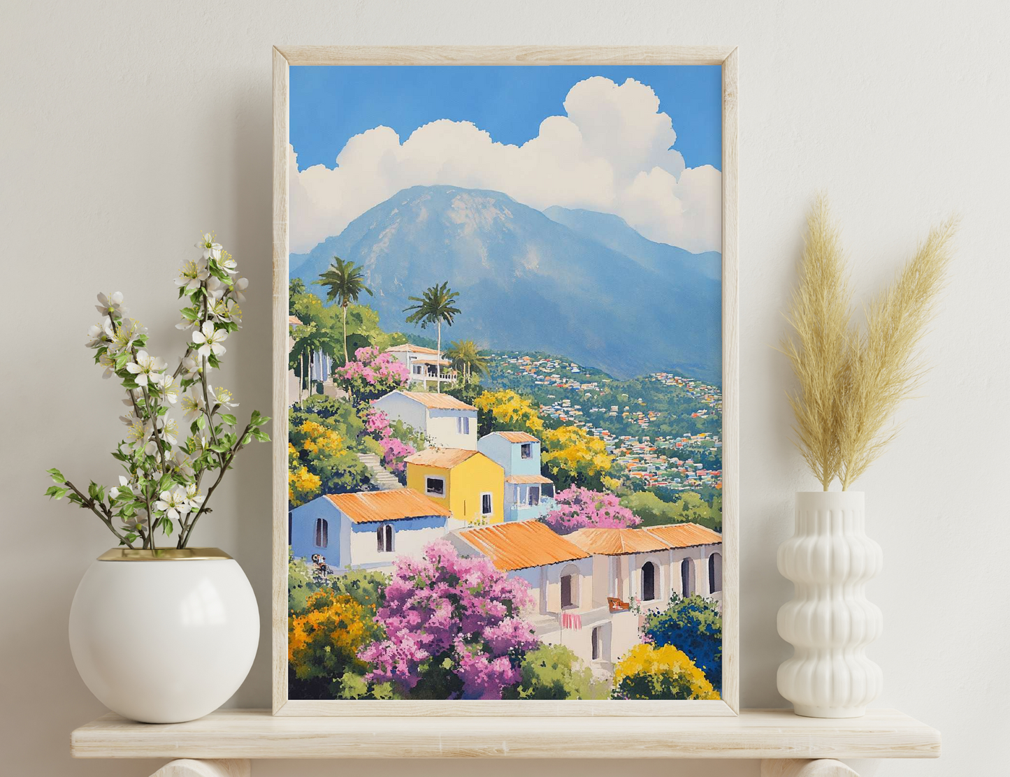 Scenic view of a colorful village nestled on a mountain slope with vibrant blooming trees and palm trees against a backdrop of majestic snow-capped mountains under a cloudy blue sky.
